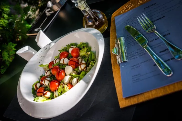  a plate of baby mozzarella salad with tomatoes and a menu 